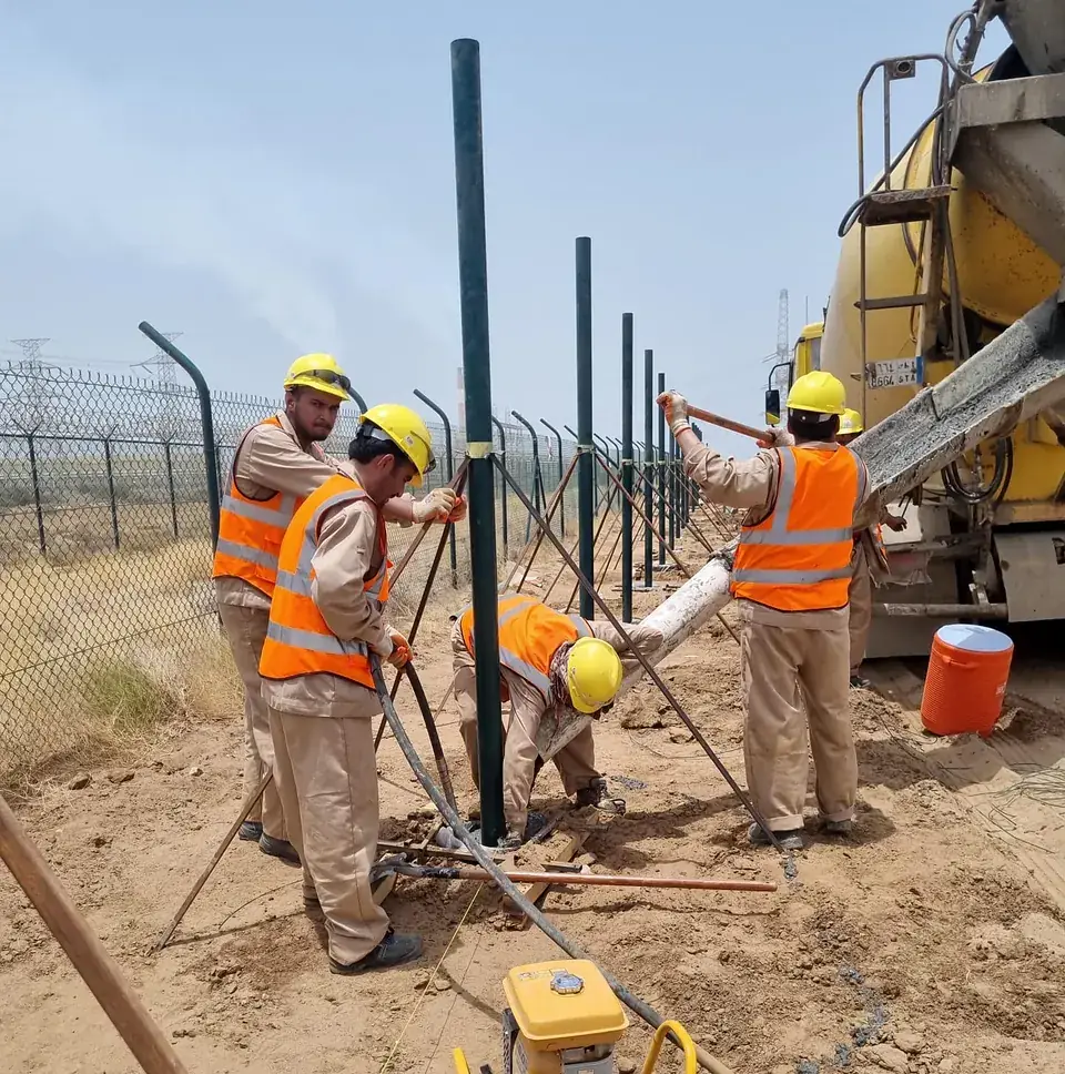 Crew setting fence posts with concrete